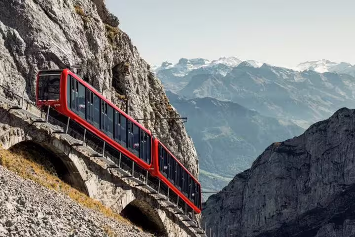 Red cogwheel train ascending Mount Pilatus with stunning Alpine views, a highlight of the Lucerne private daily tour.