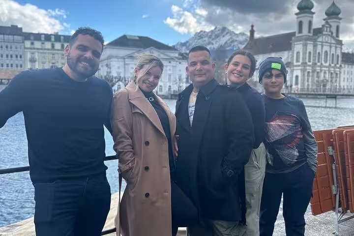 Group enjoying scenic views of Lucerne with historic architecture and snow-capped Mount Pilatus in the background.