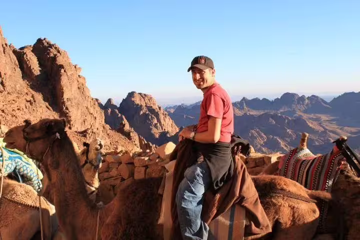 Traveler riding a camel on Mount Sinai during Sharm El Sheikh to St Catherine tour with panoramic mountain views