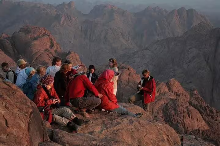 Group resting at Mount Sinai summit viewpoint at sunrise on Sharm El Sheikh to St Catherine Monastery tour