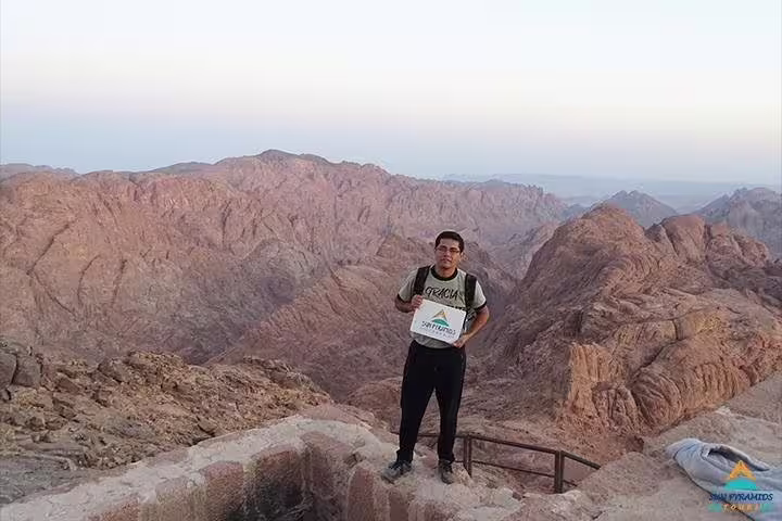 Hiker at Mount Sinai summit viewpoint at sunrise, part of private overnight Cairo tour to Saint Catherine Monastery