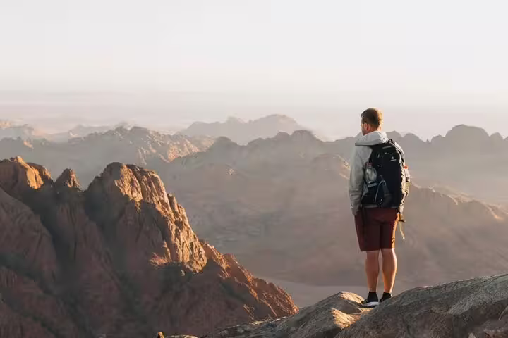 Hiker overlooking Sinai mountains at sunrise on private Mount Sinai climb from Sharm El Sheikh day trip