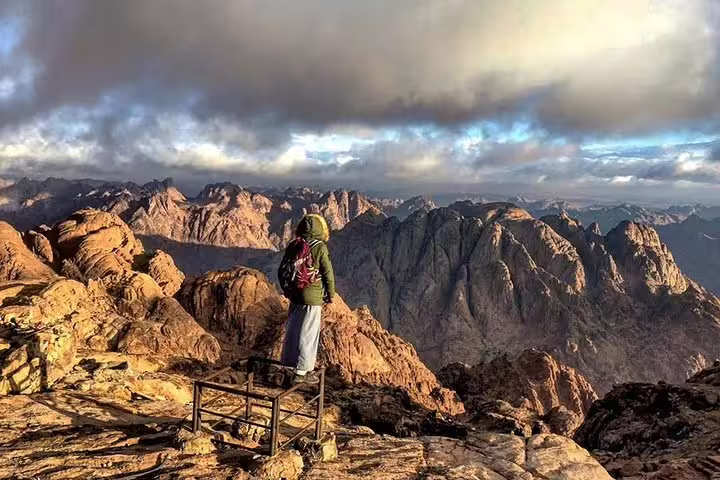 Hiker at Mount Sinai summit viewpoint on private sunrise climb, dramatic Sinai range near St Catherine Monastery