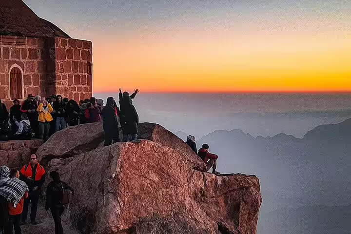 Sunrise at Mount Sinai summit near chapel with hikers, on private Sharm el Sheikh Mount Sinai climb tour