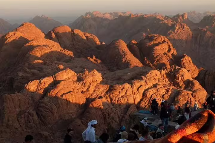 Sunrise panorama from Mount Sinai summit on climb tour, Sinai mountains glowing above St Catherine, Egypt