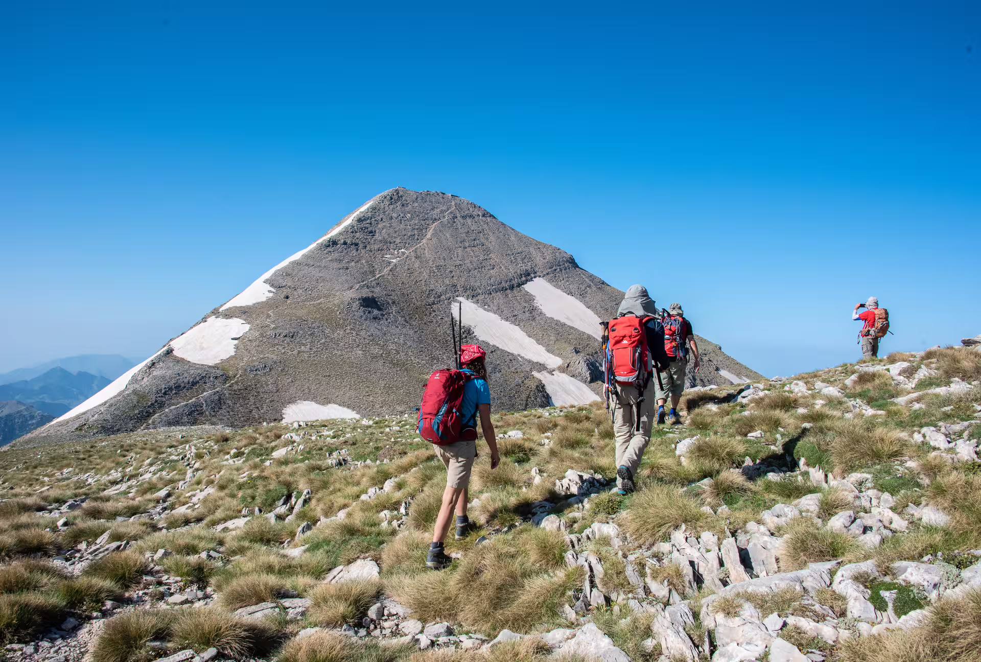 Hikers trekking toward Mount Taygetos summit at 2407m in Greece, guided alpine hike across rocky highlands
