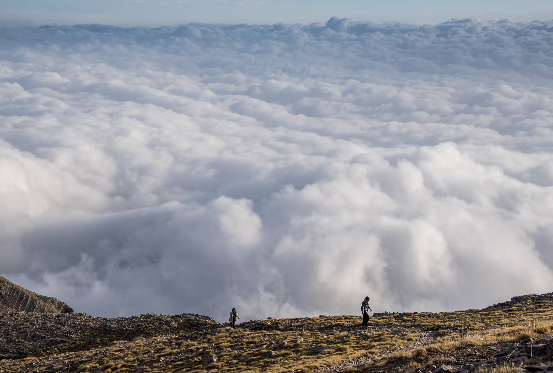 Hikers near Mount Taygetos summit above a sea of clouds, scenic 2407m peak hike in the Peloponnese, Greece