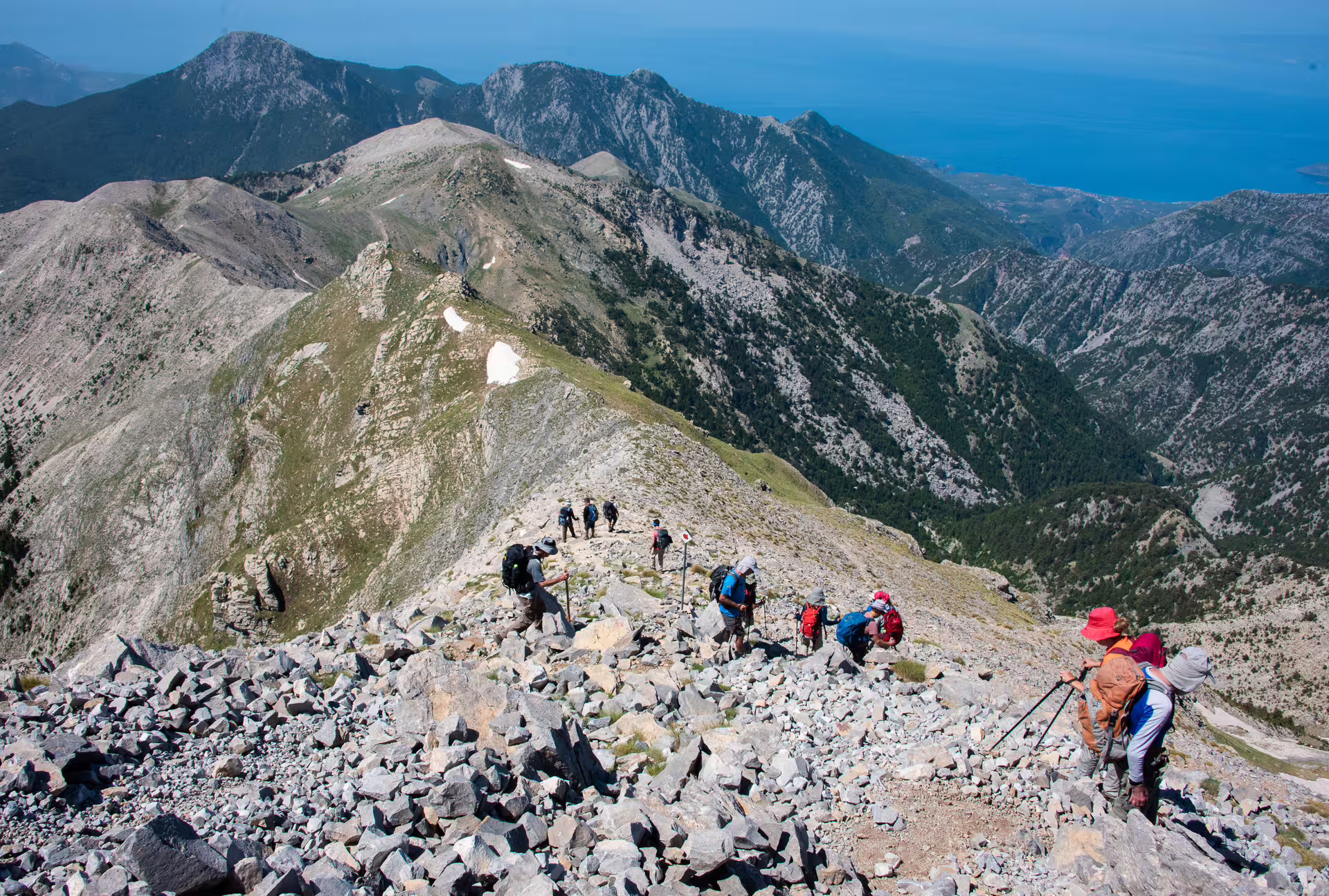 Group hiking the rocky ridge toward Mount Taygetos 2407m summit with sweeping mountain and sea views in Greece