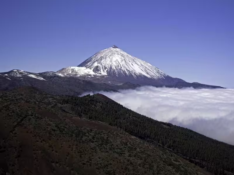 Breathtaking view of snow-capped Mount Teide above clouds, a highlight of private cruise excursions in Tenerife.
