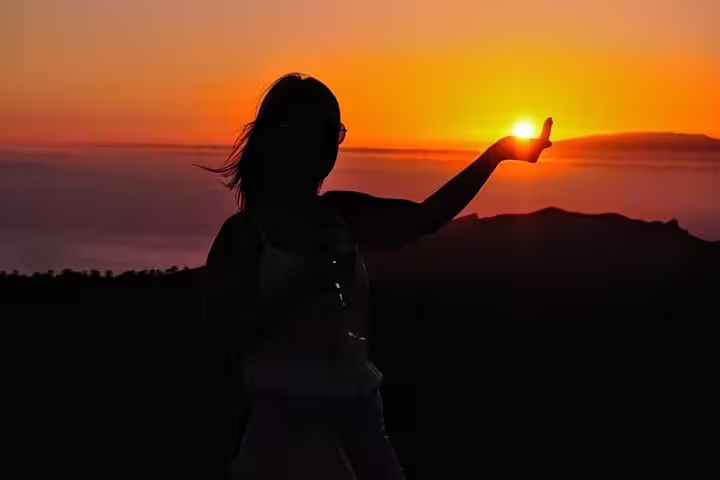 Silhouette of a person holding the sun at sunset on Mount Teide, perfect for a stargazing and dinner experience.
