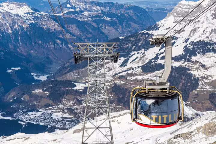 Cable car ascending Mount Titlis offering breathtaking views of snow-capped peaks and the valley below.