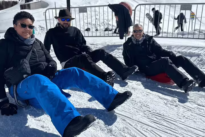 Three friends relax on the snowy slopes of Mount Titlis, dressed in winter gear, during their Engelberg adventure.