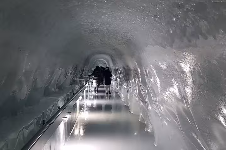 Tourists exploring the illuminated ice tunnel at Mount Titlis, experiencing the glacier's icy interior.