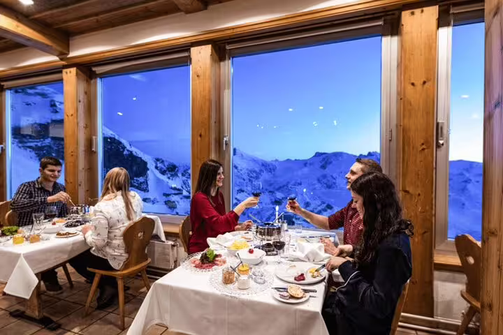 Guests enjoying a cozy dining experience with panoramic snowy mountain views at a Mount Titlis restaurant.