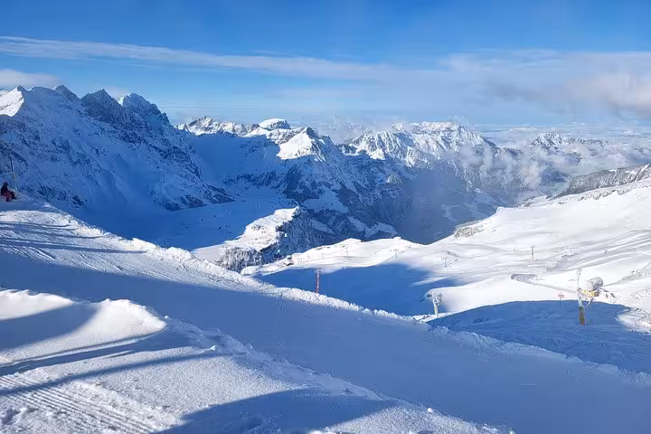 Panoramic view of snow-covered alpine landscape and mountains at Mount Titlis under a clear blue sky.