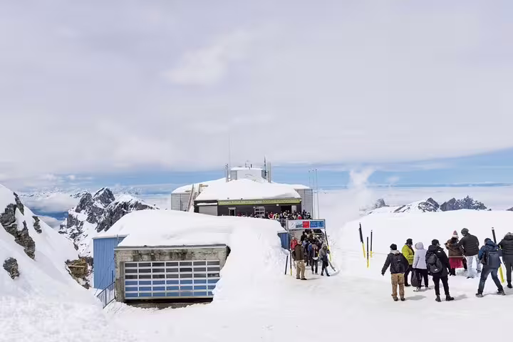 Visitors gather at the snowy peak of Mount Titlis near Engelberg, offering panoramic views of the Swiss Alps.