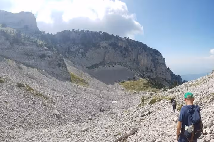 Hikers traverse rocky terrain on Mount Tomorr under a bright sky, perfect for a guided 4x4 and hiking adventure.