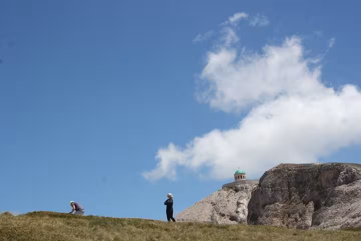 Hikers exploring the grassy landscape of Mount Tomorr under a bright blue sky, perfect for a guided 4x4 and hiking tour.