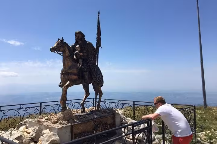 Visitor admires a historic equestrian statue on Mount Tomorr, highlighting cultural stops on the guided tour.