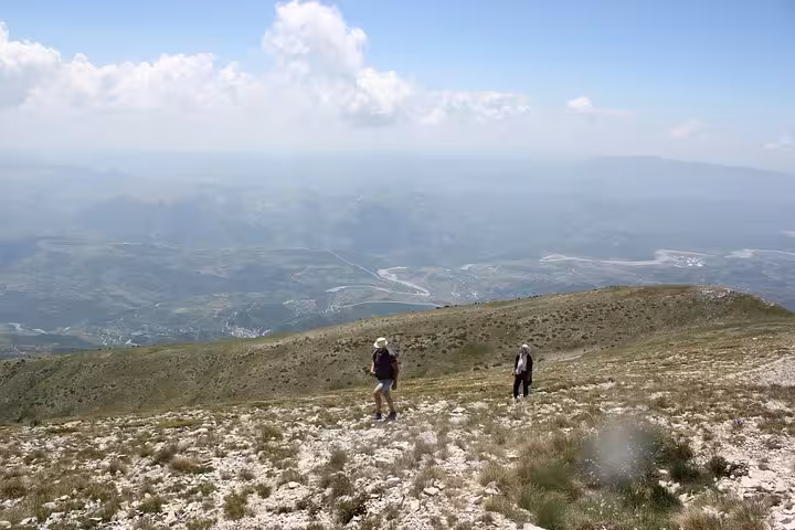 Two hikers explore the slopes of Mount Tomorr with expansive valley views, highlighting a guided adventure experience.