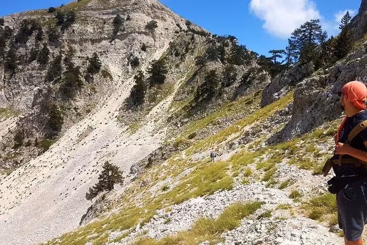 Hiker traverses rugged terrain on Mount Tomorr under clear skies, perfect for adventurous guided hiking excursions.