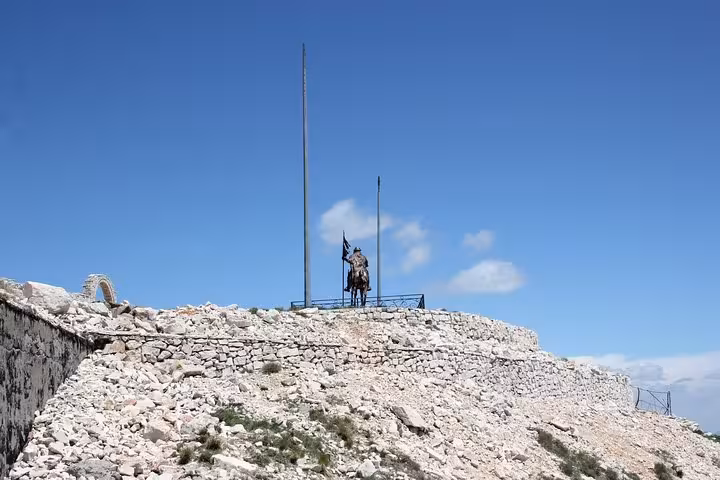 Statue atop rocky summit under clear blue skies on Mount Tomorr, ideal for adventurous guided hiking tours.