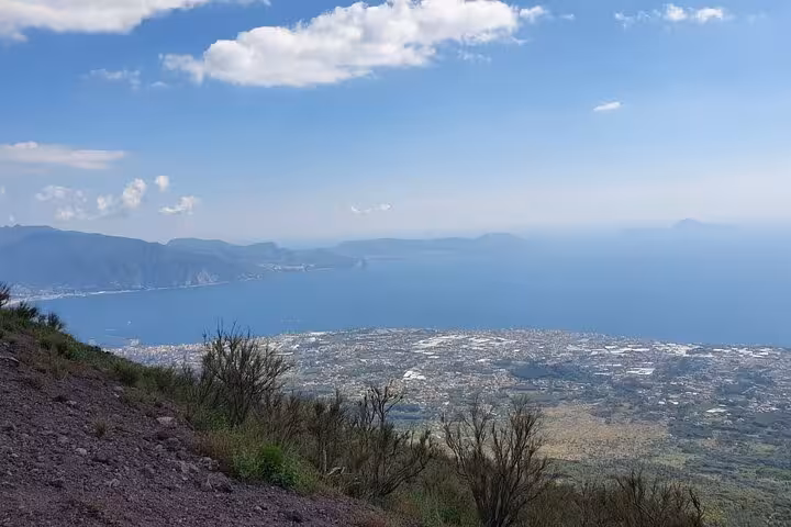 Breathtaking view from Mount Vesuvius overlooking the Bay of Naples and coastal towns under a clear blue sky.