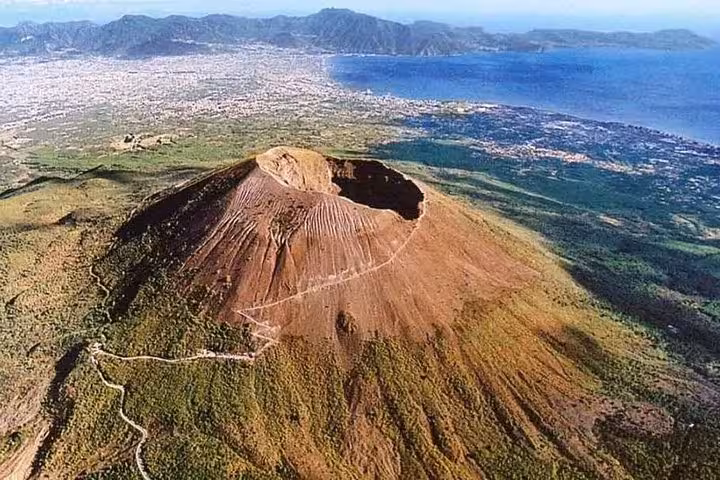 Aerial view of Mount Vesuvius showing the crater and scenic coastline, highlighting the stunning natural landscape.