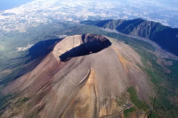 Stunning aerial shot of Mount Vesuvius' crater surrounded by lush landscapes, perfect for Amalfi Coast adventure seekers.