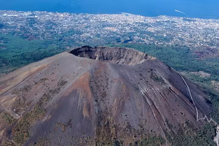 Panoramic shot of Mount Vesuvius's crater with the cityscape in the background, ideal for adventurers exploring this historic site.