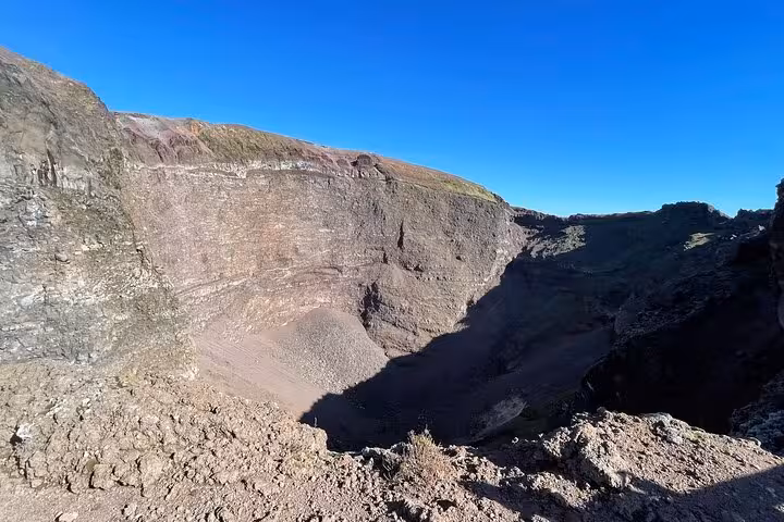 Marvel at the majestic crater of Mount Vesuvius under a clear blue sky on the Pompeii tour from Amalfi Coast.