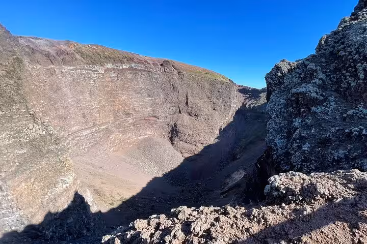 Explore the imposing crater of Mount Vesuvius under a clear blue sky on this Pompeii and wine tasting tour from Positano.