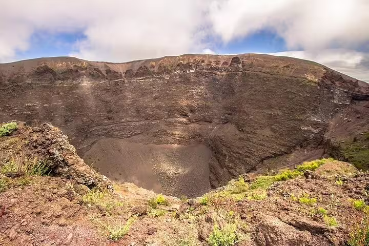 Crater rim of Mount Vesuvius with rocky slopes and greenery, visited on a guided Private Tour Positano Pompei Vesuvio