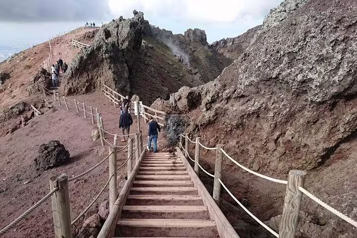 Visitors hike along the wooden path on Mount Vesuvius crater rim during Tour Sorrento Pompei Vesuvio, enjoying dramatic lava scenery