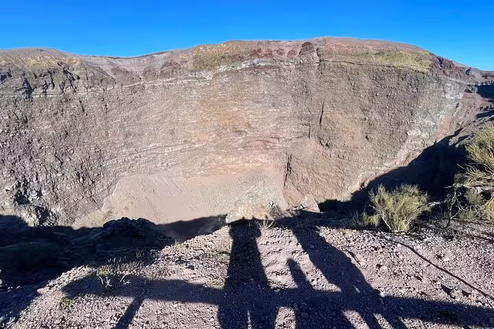 View into the massive crater of Mount Vesuvius, showcasing its rugged terrain on a sunny day during a small group tour.