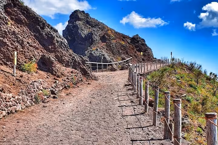 Scenic trail on Mount Vesuvius with rugged terrain and clear blue skies, perfect for a guided tour experience.