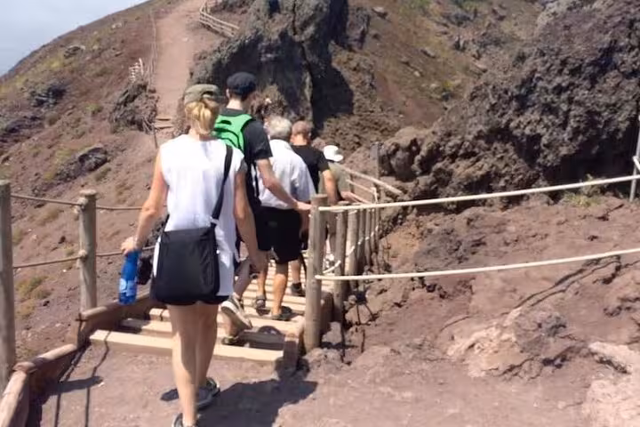 Tourists hike along the scenic trails of Mount Vesuvius, showcasing rugged volcanic landscapes and clear pathways.