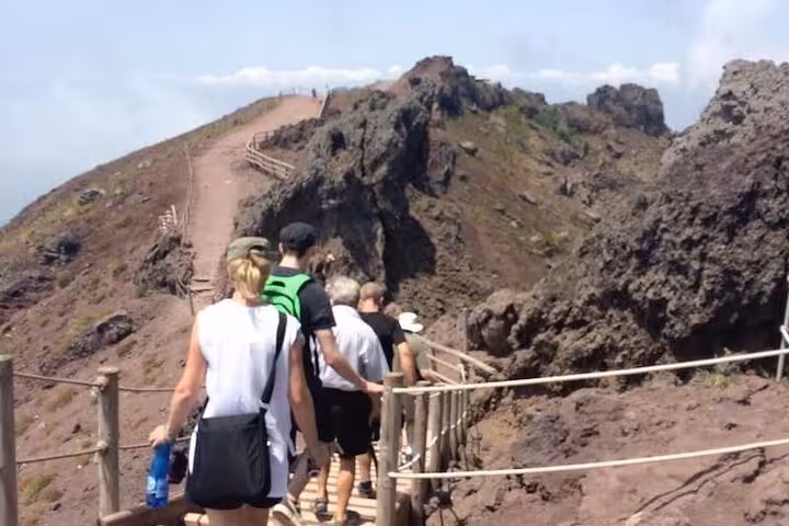 Visitors hike along the rocky trails of Mount Vesuvius, enjoying scenic views and guided tours from Sorrento.