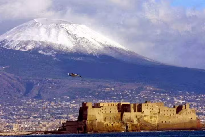 Snow-capped Mount Vesuvius rising behind Castel dell’Ovo and the Bay of Naples on a clear day during a private half-day tour