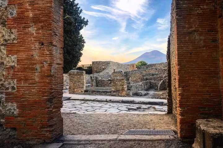 Framed view of Mount Vesuvius through Pompeii's ancient stone archways, ideal for cultural and wine tasting tours.