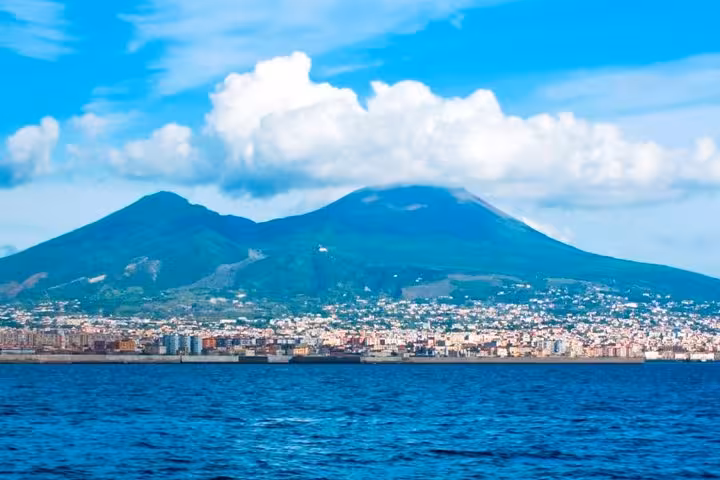 Scenic view of Mount Vesuvius with a city skyline and blue sea, offering a picturesque backdrop for a private tour.
