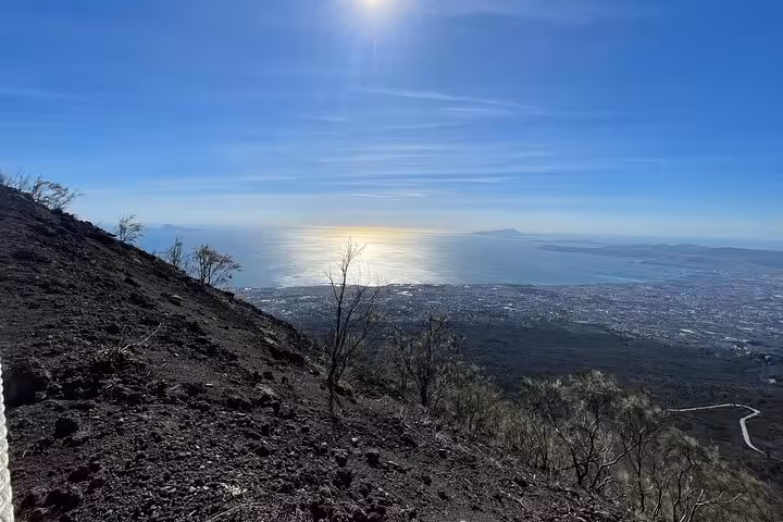 Stunning panoramic view from Mount Vesuvius summit, sunlight reflecting on the sea near Naples.