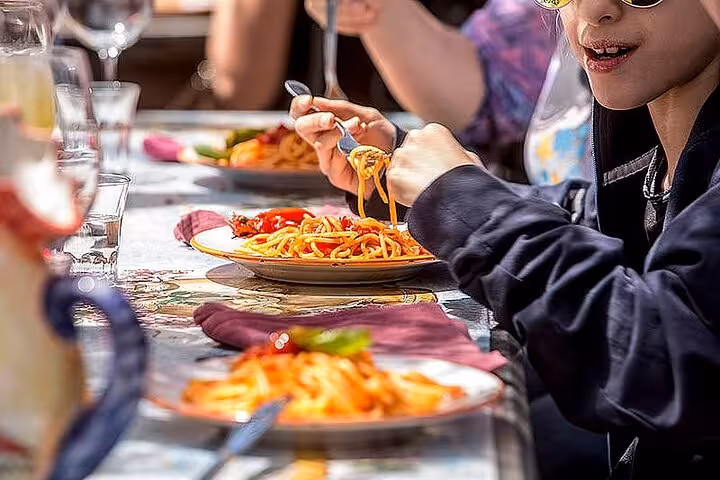 Guests savor spaghetti at an outdoor lunch setting on the Mount Vesuvius tour, showcasing Italian culinary delights.