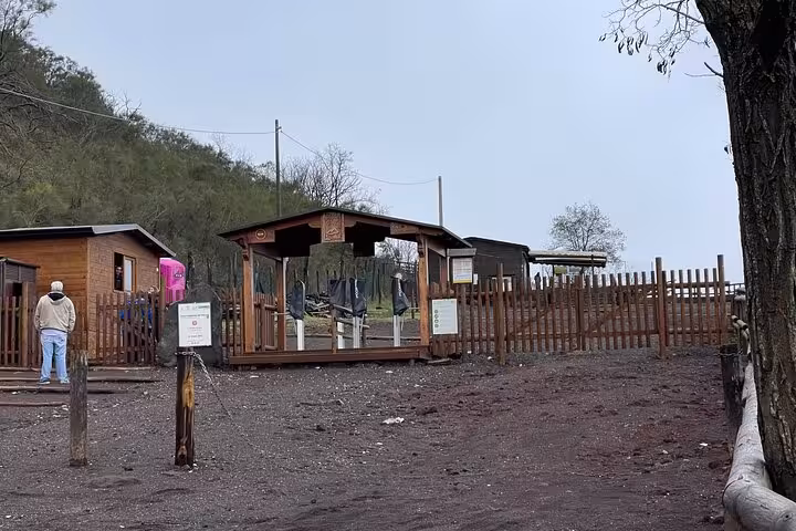 Entrance to Mount Vesuvius trail with wooden structures surrounded by greenery on Pompeii, Vesuvius & wine tour.