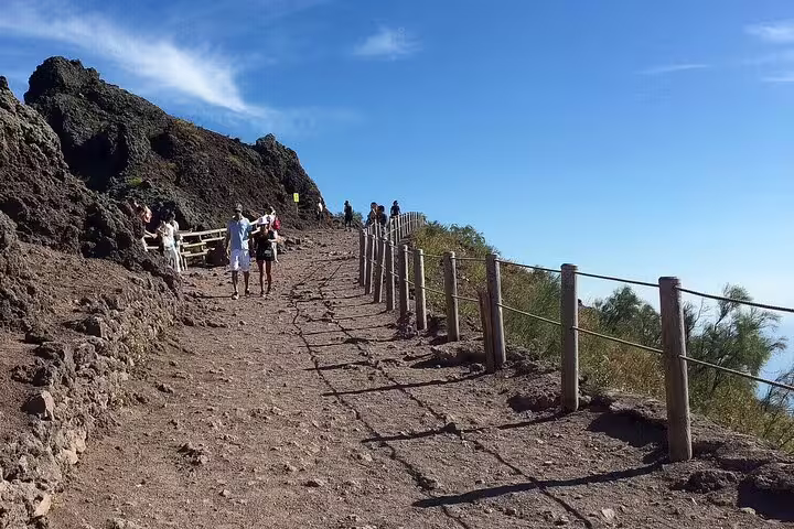 Hikers on Mount Vesuvius trail with railings and lava rocks, VIP small-group guided tour with ticket