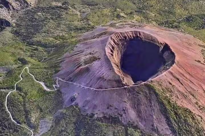 Aerial view of Mount Vesuvius volcanic cone and crater surrounded by green slopes on the Tour Sorrento Pompei Vesuvio excursion