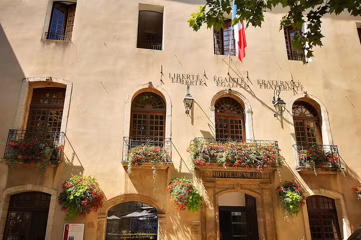 Moustiers-Sainte-Marie town hall facade with French flag and flowered balconies on private day trip