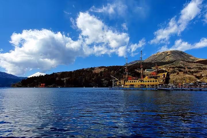 Colorful pirate ship docked at Lake Ashi with Mt. Fuji and lush hills in the background, perfect for a Hakone tour.