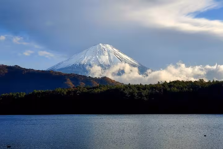 Stunning view of snow-capped Mt. Fuji from Yokohama Port, surrounded by lush forests and serene lake waters.