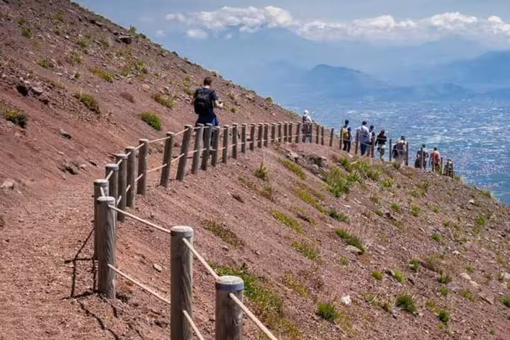 Visitors walking along a scenic path on Mt. Vesuvius with panoramic views on a volcano and ancient ruins tour.
